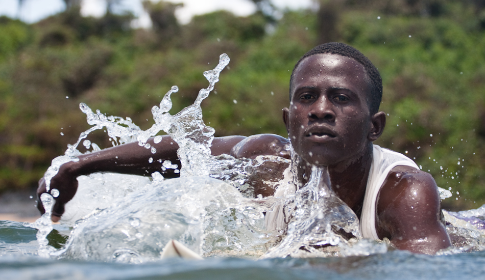 Benjamin McCrumuda has the uncanny ability to summon the seas.  If the ocean goes dormant for too long, he simply slaps the water and bellows out “Kway-Pu-Na!”  This phrase translates to “big sea wave come” in Benjamin’s native tongue of Vai and when he asks, the ocean answers. Photo: Brody/<a href=\"https://www.surfresource.org/\" target=_blank>SurfResource.org</a>
